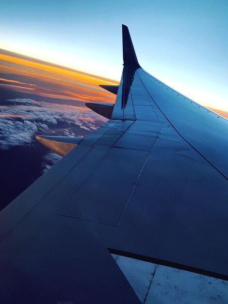 Airplane wing against sky during sunset