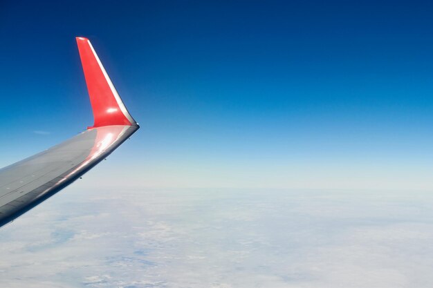 雲の上の飛行機の翼 航空機の窓からの空中平面図 厚い白い青い雲