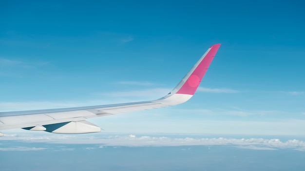 飛行機の翼、雲、青い空が飛行機の窓から見えてきました。