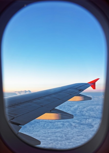 飛行機の翼とイルミネーターを通して見た雲