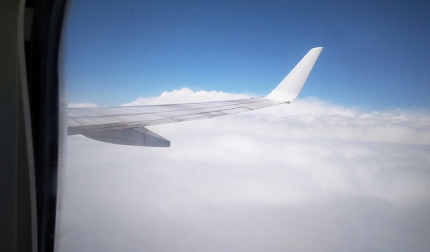 Airplane wing from plane window. View from the aircraft's airplane to the wing in the sky above the clouds. Flight by plane.