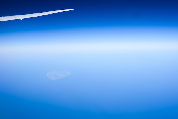 Airplane wing over ocean against blue sky