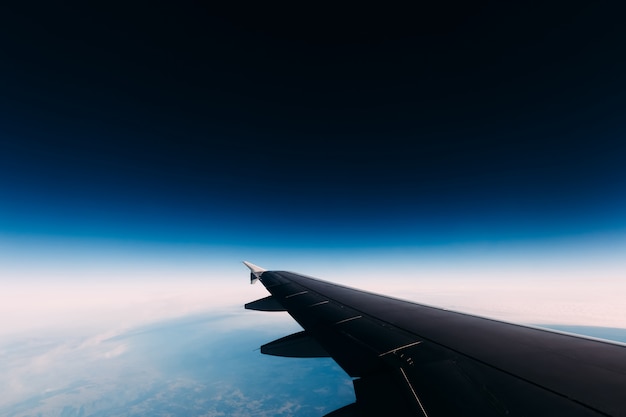 Airplane wing view to a blue mysterious space