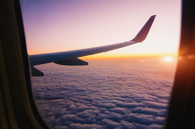 飛行機の窓から見た光のフレアで日の出の飛行機の翼。 -画像