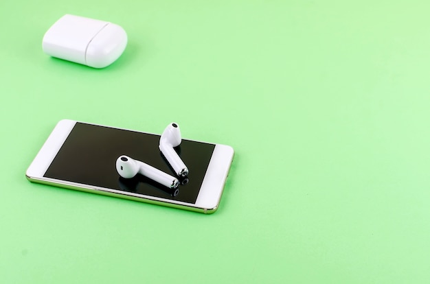 Airpods for smartphone and a green background. Copy Space