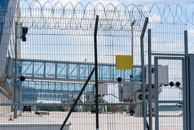 Airport fence grille on the background of passenger bridges for boarding passengers. Place for the test on the plate.