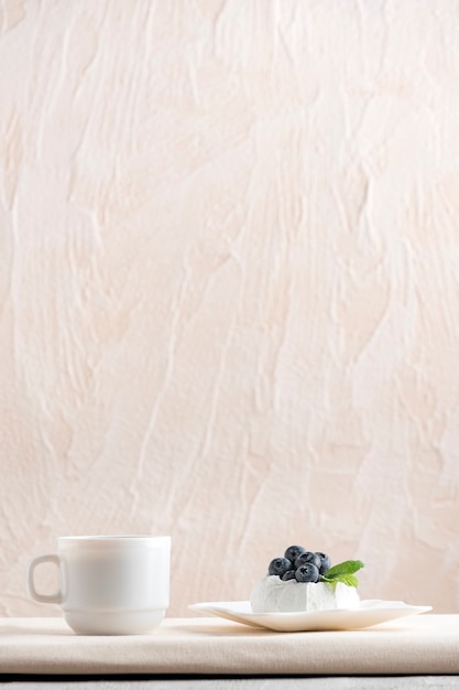 Airy cake with fresh berries on saucer and cup of coffee. Vertical frame, copy space.