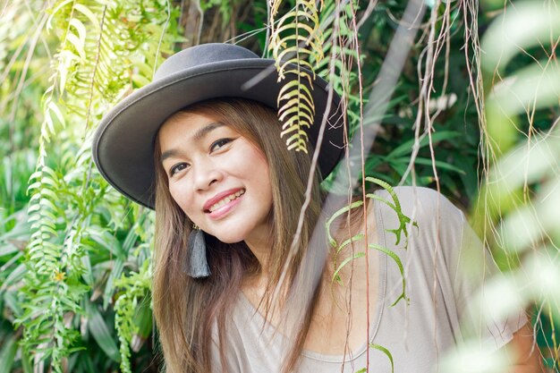 Aisan 관광 여자 착용 모자 포즈와 녹색 자연 배경으로 미소