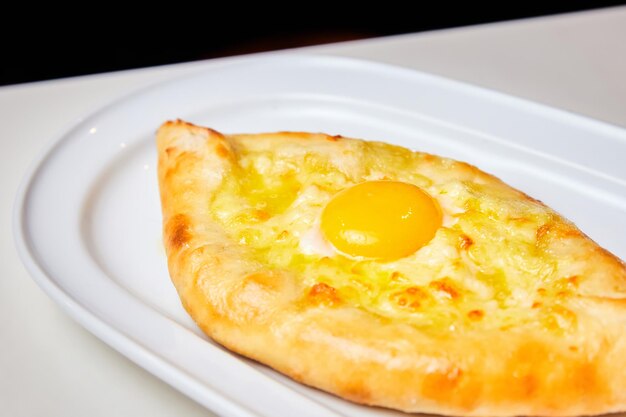 Ajarian traditional flatbread khachapuri or hachapuri with cheese egg and butter on a plate