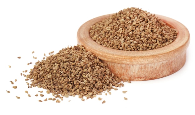 Ajwain seeds in a wooden bowl over white background