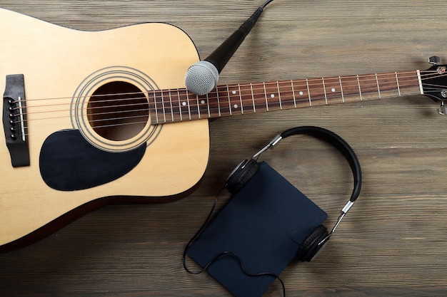 Akoestische gitaar koptelefoon notebook en microfoon op houten achtergrond