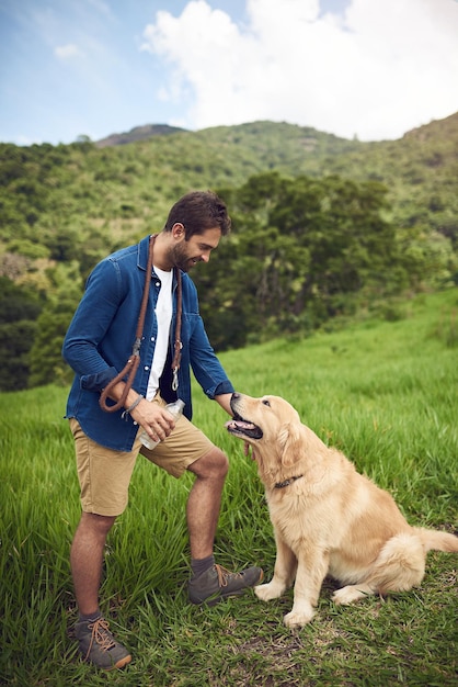 Al op adem komen Volledig shot van een knappe jonge man die tijdens een wandeling met zijn golden retriever staat