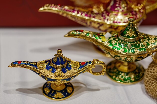 Photo aladdin's mysterious lamp precious golden magic lamp on blurred background fairy tales and wish fulfillment concept background with selective focus and copy space close up of gold decorative lamps