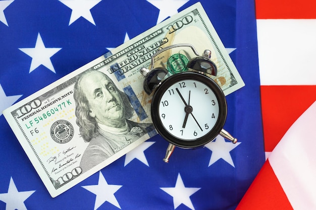 Photo alarm clock and 100 dollar banknote on american flag