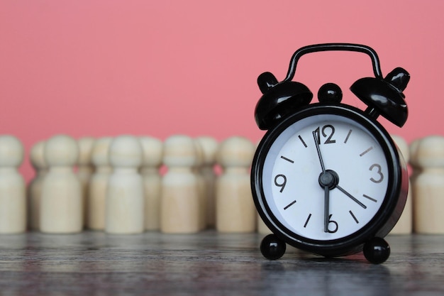 写真 目覚まし時計と木の人形 時間管理 時給 労働時間と休憩時間のコンセプト