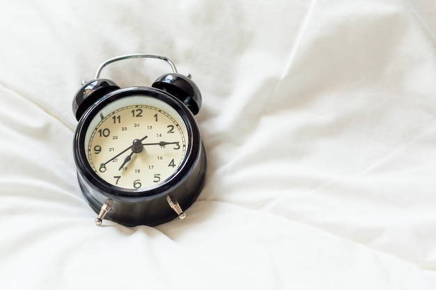 自宅のベッドの目覚まし時計。朝の時間の背景のコンセプト。コピースペース