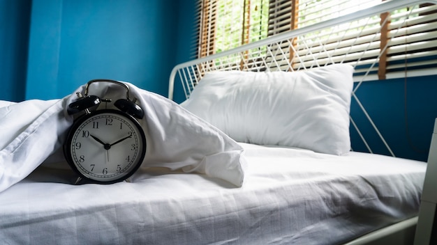 Alarm clock on the bed and pillow background