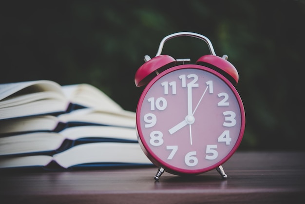 alarm clock and books on the wood table with bokeh background