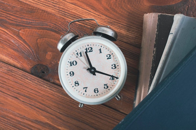 Alarm clock and books on a wooden table