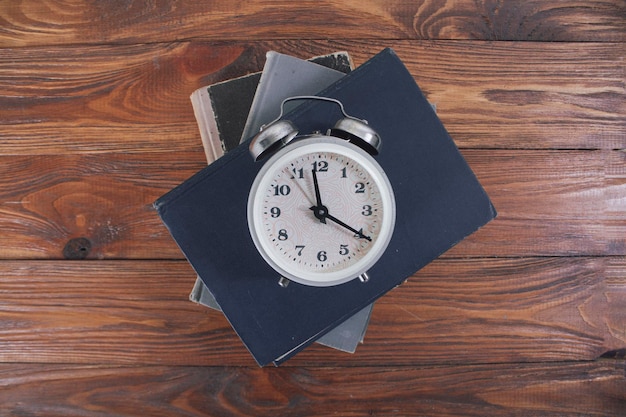 Alarm clock and books on a wooden table