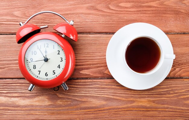 Alarm clock and coffee on a wooden table. Coffee time.