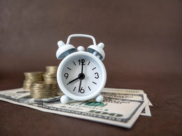 Alarm clock, coins and banknotes on a dark background. The idea of business, Finance concept and saving money and time.