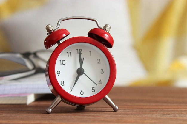 Alarm clock on a colored background a cup of coffee and stationery