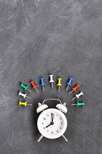 Alarm clock, colored pencils and stationery on blackboard