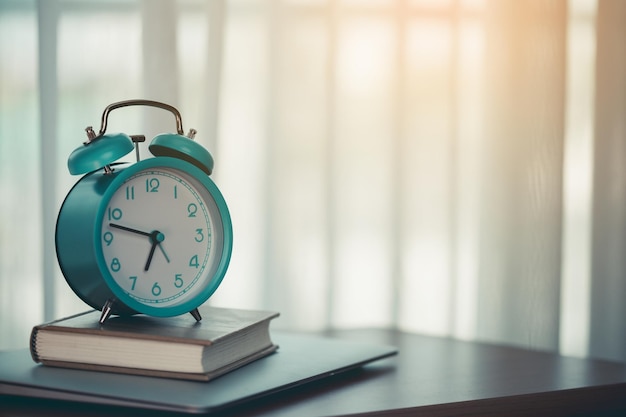 An alarm clock on a diary notebook and laptop