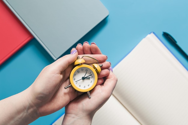 Alarm clock in female hands the concept of study work and time planning