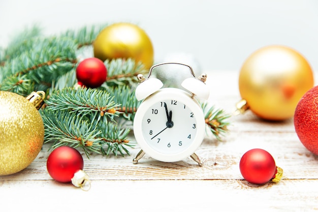 Alarm clock, fir branches and Christmas balls on a wooden background. Christmas background or postcard.