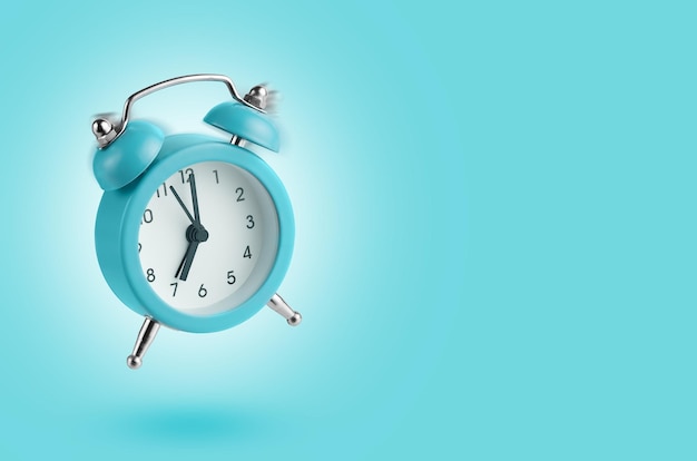 Alarm clock flying over blue background Copy space