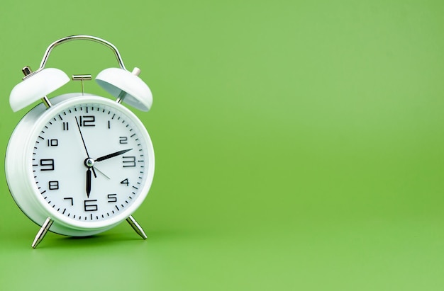 Alarm clock on green background time concept working with time precious time