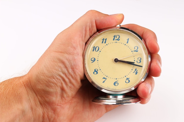 Alarm clock in human hand on a white surface