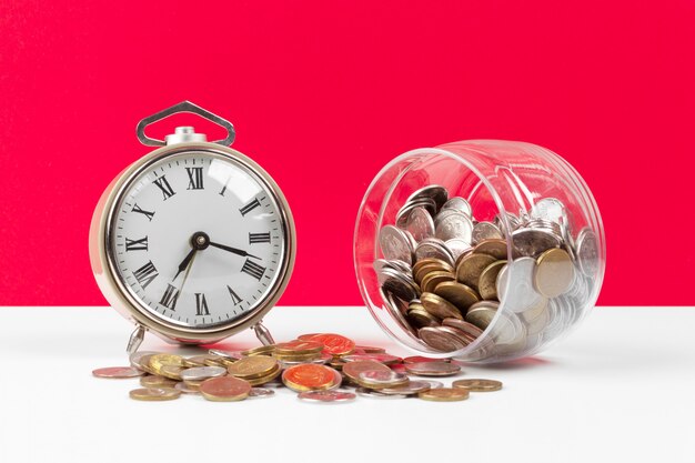 Alarm clock and money coins on the table.