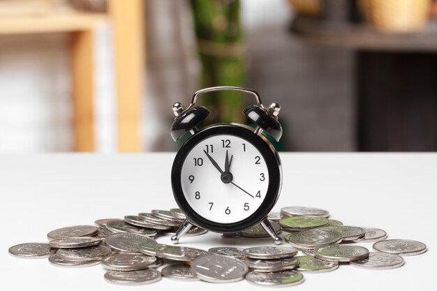 Alarm clock and money coins on the table.