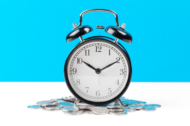 Alarm clock and money coins on the table.