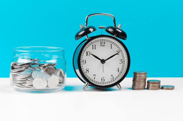 Alarm clock and money coins on the table.