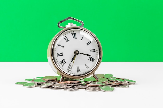 Alarm clock and money coins on the table.