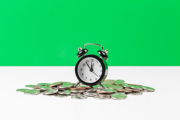 Alarm clock and money coins on the table.