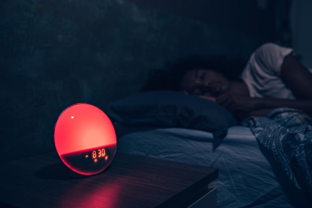 Alarm clock near sleeping woman