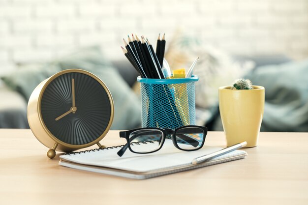 Alarm clock and office stationery objects close up on wooden table