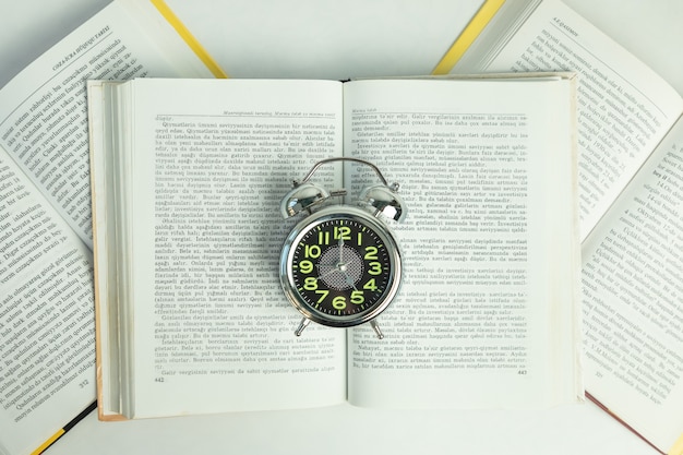 Alarm clock on the open books, top view