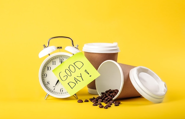 Alarm clock paper cup paper reminder and coffee beans on yellow background