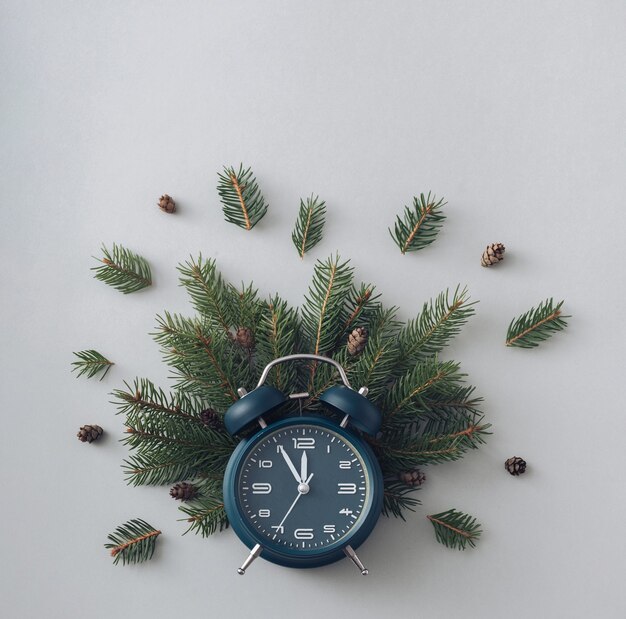 Alarm clock and pine branches on a gray background concept of winter holidays and vacations flat lay