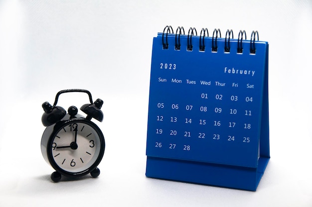 白い背景に2023年2月のカレンダーで9時39分を指す目覚まし時計時間とカレンダーのコンセプト