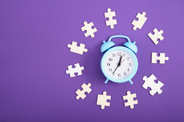 Alarm clock and puzzles on purple background