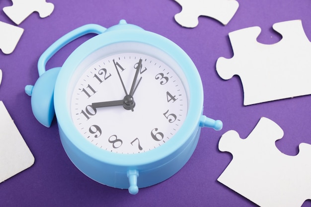 Alarm clock and puzzles on purple background