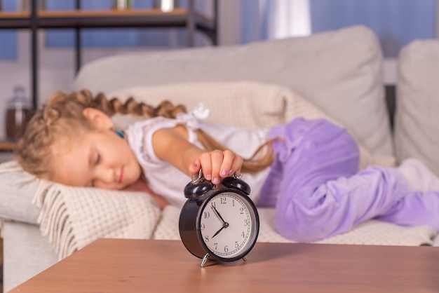 Photo the alarm clock rings at home the girl screams and does not want to get up to school