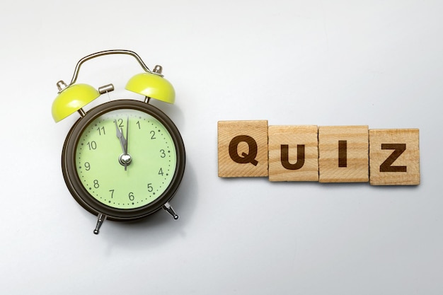 Alarm clock and a row of wooden cubes with quiz text